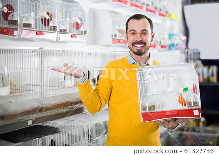 Smiling man enjoying his purchase of canary bird Smiling man enjoying his purchase of canary bird 61322736