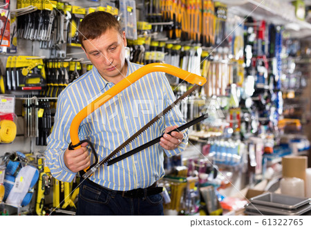 Adult male is looking on new hacksaw in tools store 61322765