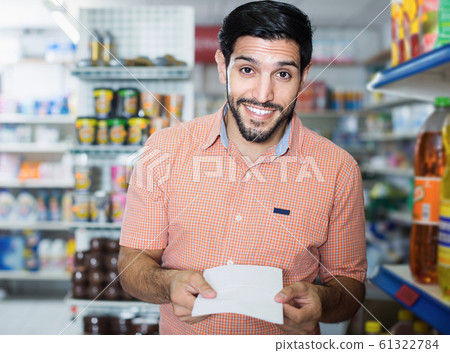 Smiling male with note for shopping in shop 61322784
