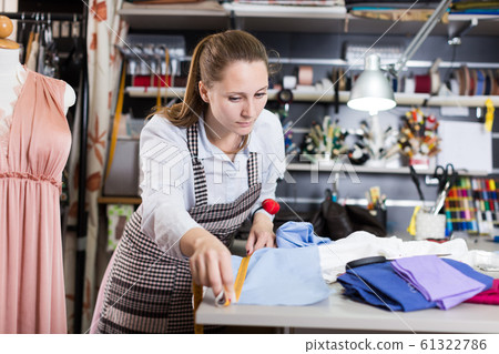 Female seamstress is cutting textile for create new dress Female seamstress is cutting textile for create new dress 61322786