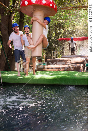 Friends help each other overcome water obstacles in theme park Friends help each other overcome water obstacles in theme park 61322788