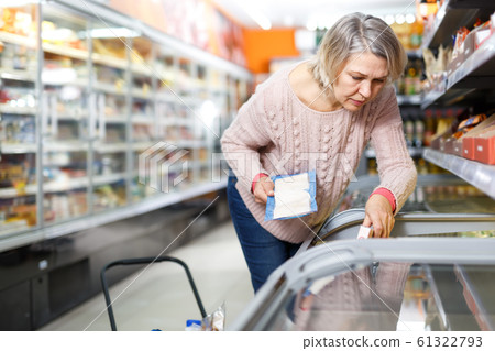 Casual mature woman looking for fish in freezer 61322793