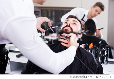 Man forming beard of client into new shape Man forming beard of client into new shape 61322805