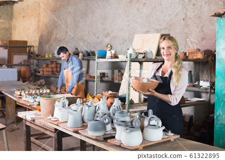 Portrait of glad woman pottery worker with ceramic crockery Portrait of glad woman pottery worker with ceramic crockery 61322895