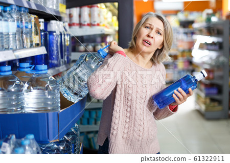 Tense mature woman lifting heavy bottle water Tense mature woman lifting heavy bottle water 61322911