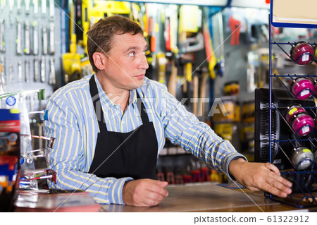 Attentive seller man in store is trading tools 61322912