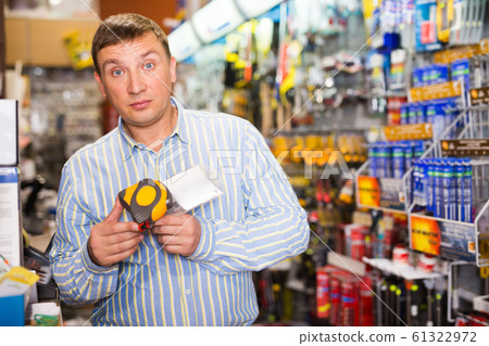 Worker looks at tape measure in store 61322972