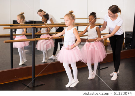 Girls practicing elements on ballet barre Girls practicing elements on ballet barre 61323074