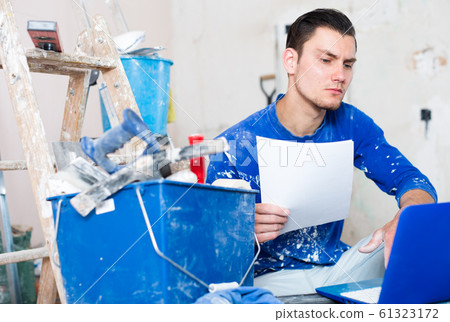 Serious builder with papers and laptop Serious builder with papers and laptop 61323172