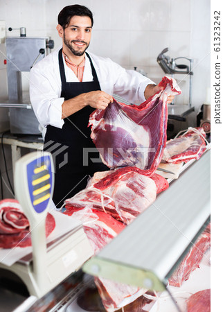 Smilling butcher is offering meat to clients in market. Smilling butcher is offering meat to clients in market. 61323242