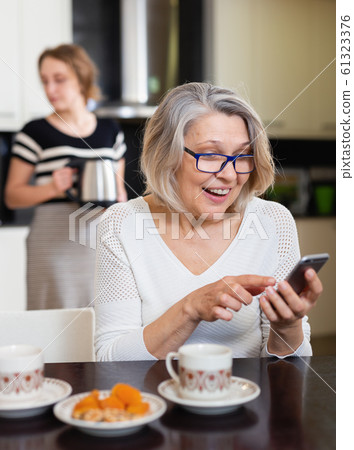 Mature woman using phone Mature woman using phone 61323376