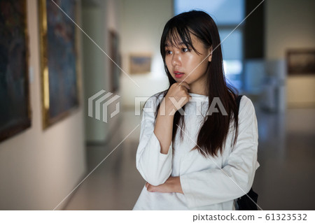 Chinese female visitor looking at artwork painting in the museum Chinese female visitor looking at artwork painting in the museum 61323532