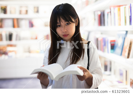 Young female student choosing new books on shelves Young female student choosing new books on shelves 61323601