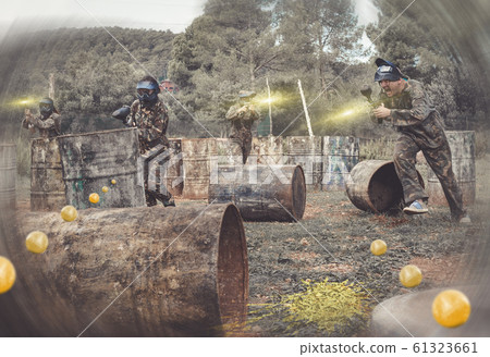 Paintball players aiming and shooting with guns Paintball players aiming and shooting with guns 61323661