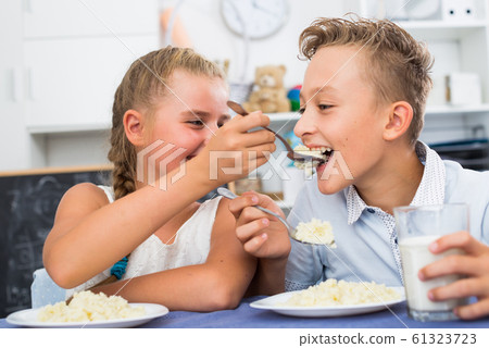 Girl is feeding her brother Girl is feeding her brother 61323723