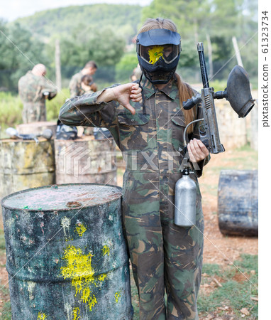Female player in camouflage and black mask with traces of paint from hit markers Female player in camouflage and black mask with traces of paint from hit markers 61323734