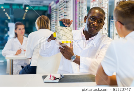 Boy choosing glasses and man ophthalmologist holding mirror Boy choosing glasses and man ophthalmologist holding mirror 61323747