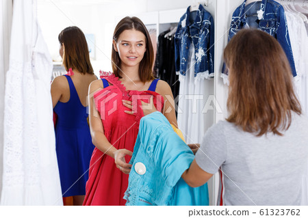 Girl choosing dress with help of assistant 61323762