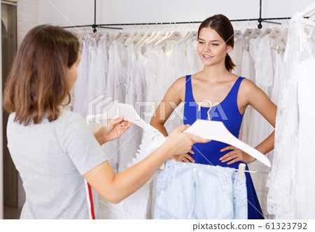 Woman choosing wedding dress with help of assistant Woman choosing wedding dress with help of assistant 61323792