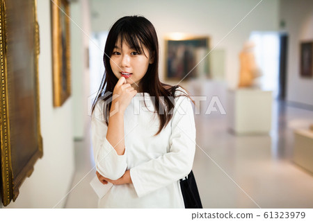 Chinese female visitor looking at artwork painting in the museum indoors Chinese female visitor looking at artwork painting in the museum indoors 61323979