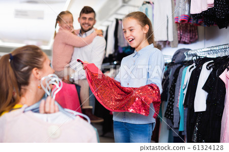 Smiling girl with mother fitting new dress in shop 61324128