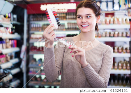 interested female customer deciding on make-up items in cosmetics shop interested female customer deciding on make-up items in cosmetics shop 61324161