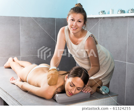 Young masseur female is doing massage to woman client Young masseur female is doing massage to woman client 61324255