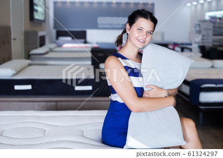 Female sitting with pillow on mattress Female sitting with pillow on mattress 61324297