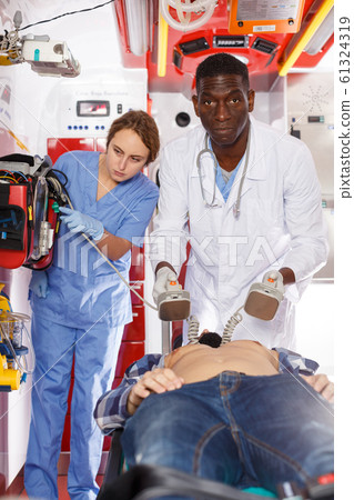 Emergency doctor using defibrillator 61324319