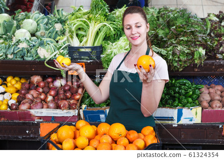 Saleswoman holding oranges in market Saleswoman holding oranges in market 61324354