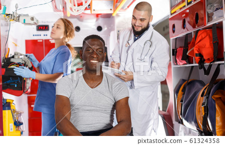 Smiling afro man sitting on stretcher Smiling afro man sitting on stretcher 61324358