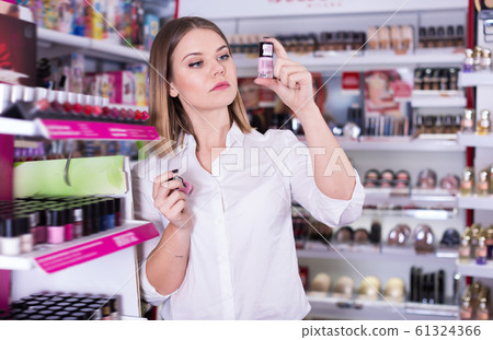 Positive girl choosing color of nail polish Positive girl choosing color of nail polish 61324366