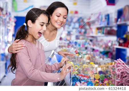Woman with emotional daughter choosing candies in the candy shop Woman with emotional daughter choosing candies in the candy shop 61324418