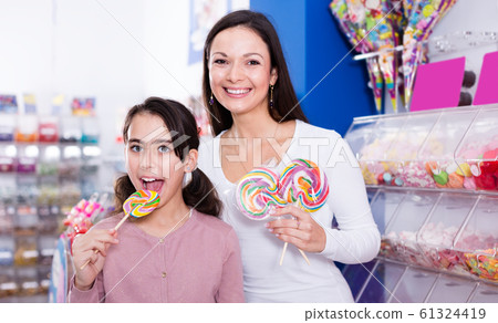 mother with daughter standing with lollipop in store 61324419