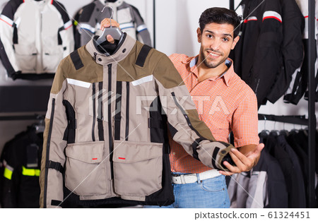 Man is demonstrating new jacket for motorbike in the store. Man is demonstrating new jacket for motorbike in the store. 61324451