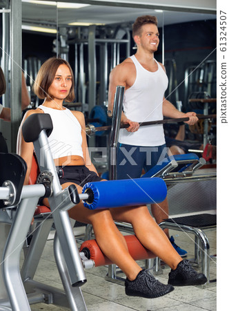 Woman making leg extension exercise using gym machinery 61324507