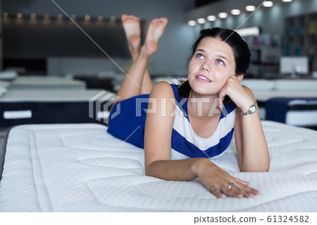 Portrait of cute female lying on soft mattress Portrait of cute female lying on soft mattress 61324582