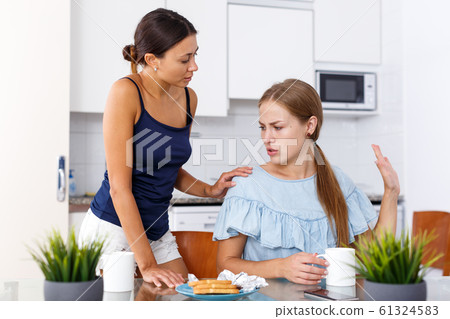 Upset young women friends quarrelling and drinking tea at home Upset young women friends quarrelling and drinking tea at home 61324583