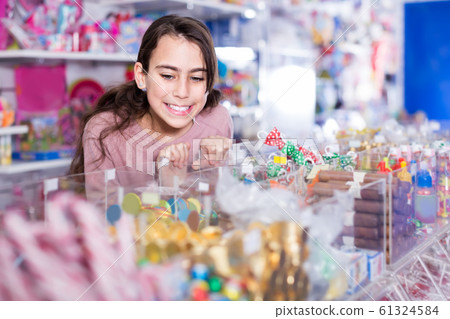 Young schoolgirl delighted with choosing lollipop in store Young schoolgirl delighted with choosing lollipop in store 61324584