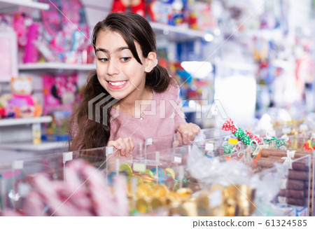 Emotional small girl choosing sweet candies in the candy shop 61324585