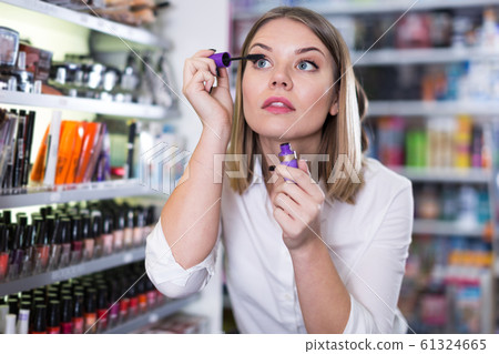 Young woman testing mascara before buying 61324665