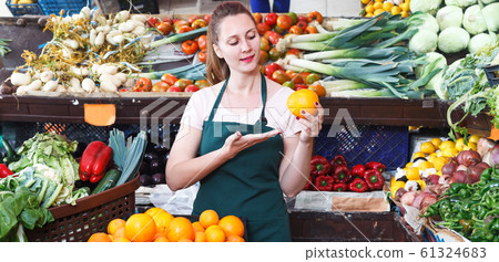 Saleswoman holding oranges in market Saleswoman holding oranges in market 61324683