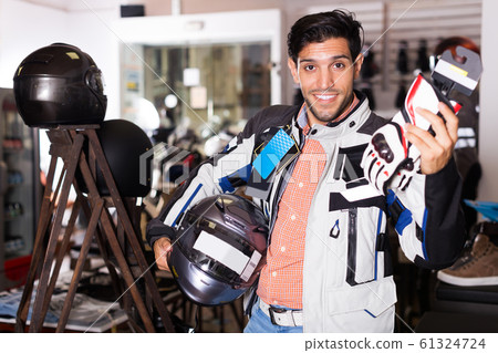 customer in jacket with helmet is choosing gloves customer in jacket with helmet is choosing gloves 61324724