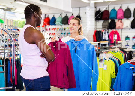 Portrait of happy man and woman holding sportswear in sporting g Portrait of happy man and woman holding sportswear in sporting g 61324747
