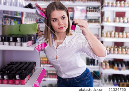 Positive girl choosing new nail polishes in shop 61324760