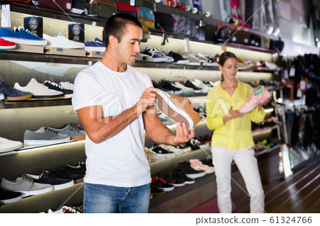 Positive man looking for new casual shoes at shopping mall Positive man looking for new casual shoes at shopping mall 61324766