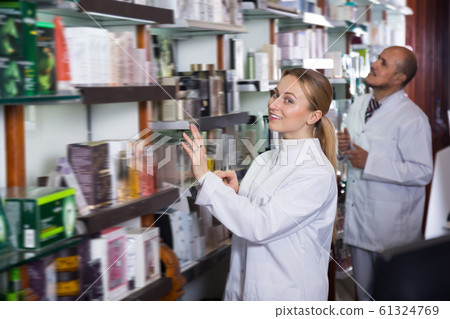 Smiling pharmacists standing next to shelves Smiling pharmacists standing next to shelves 61324769
