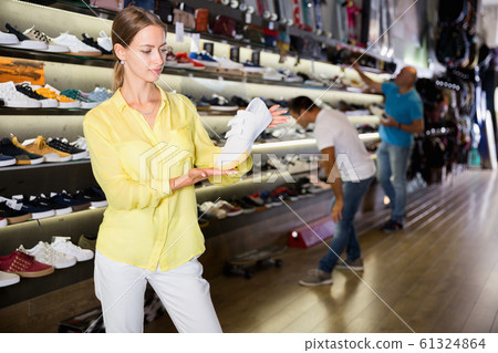 Young positive woman shopping casual sneakers in modern store Young positive woman shopping casual sneakers in modern store 61324864