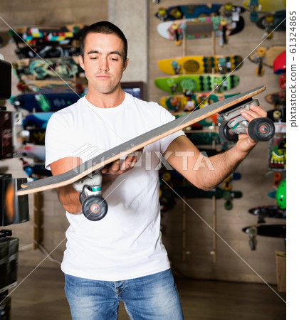 Portrait of man choosing skateboard in sporting goods store Portrait of man choosing skateboard in sporting goods store 61324865