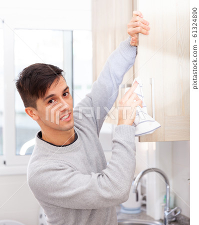 Positive man doing cleaning in the kitchen 61324890